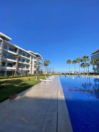 a swimming pool in front of a building with palm trees at Les belles terrasses mansouria in Mansouria