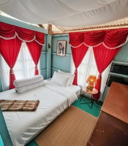 a bedroom with a bed with red drapes at Sunrise Komodo Homestay in Komodo