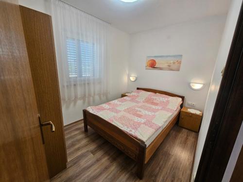 a small bedroom with a bed and a window at Apartmani Marko in Nin
