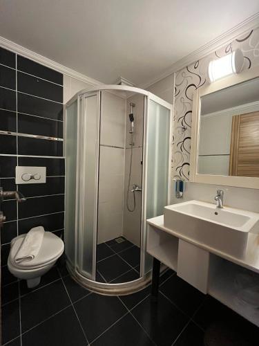 a bathroom with a shower and a toilet and a sink at Uğur Otel in Kaş