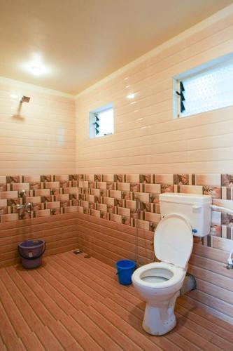 a bathroom with a toilet in a wooden room at Nature's Nook in Ganeshgudi