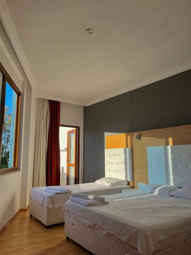 a bedroom with two beds and a large window at Uğur Otel in Kaş