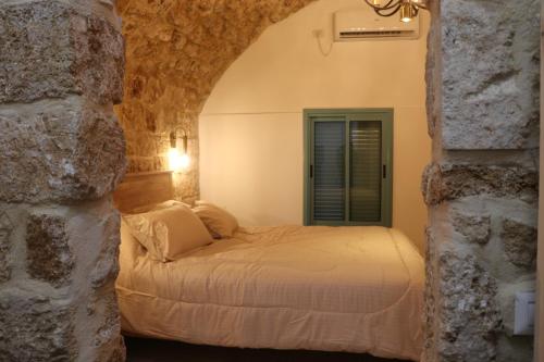 a bedroom with a bed in a stone wall at Ayham dream house in Acre