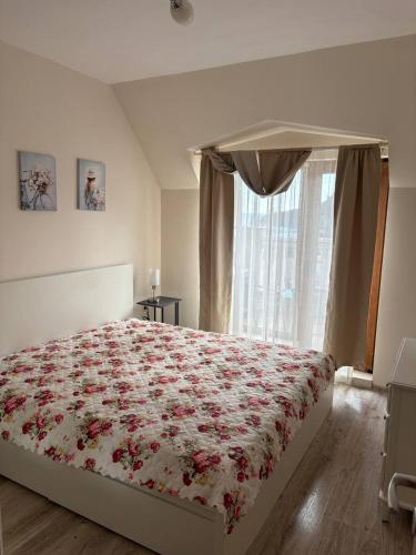 a bedroom with a bed with a floral bedspread and a window at Видовые 2-комнатное апартаменты в комплексе Varna South Bay in Asparukhovo