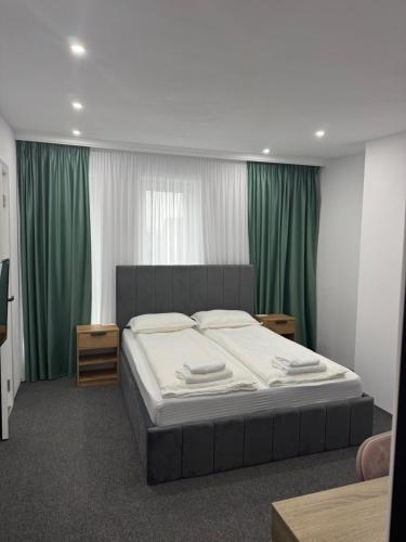 ein Schlafzimmer mit einem großen Bett und grünen Vorhängen in der Unterkunft Casa Noa in Marginea