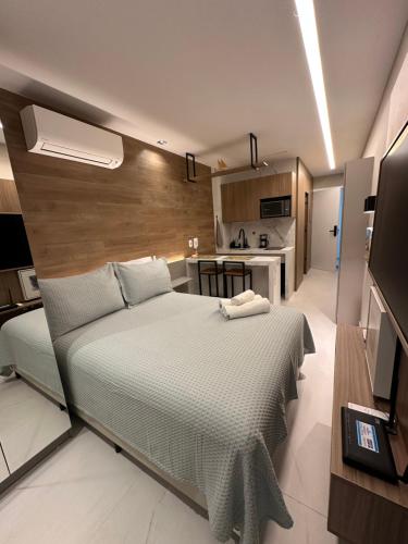 a bedroom with a large bed and a kitchen at Maré alta flat 213 in Tamandaré