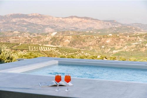 two wine glasses sitting on a table next to a swimming pool at Samiro Private Villa - Heated Pool & Hot tub in Áyios Míron