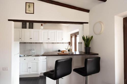 a kitchen with white cabinets and black chairs at Vista Menaggio Centro by LoveComo in Menaggio