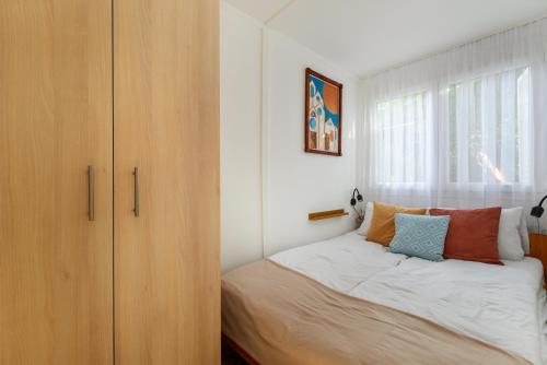 a bedroom with a bed next to a window at Csendliget Apartman in Dunavarsány