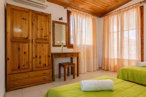 a bedroom with two beds and a desk and a mirror at Ionian Breeze Apartments in Kavos