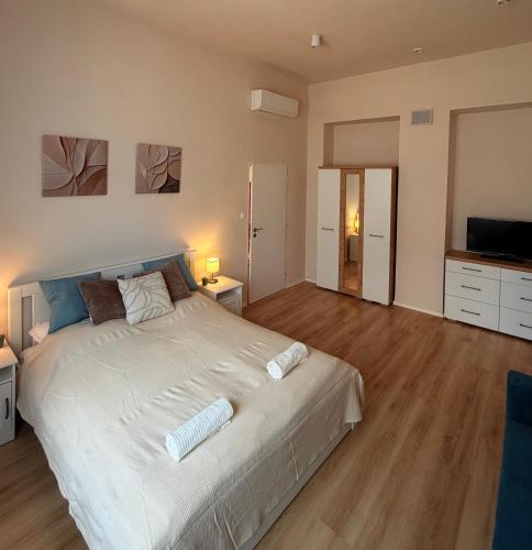 a bedroom with a large white bed and a television at Hedera Home in Komárno