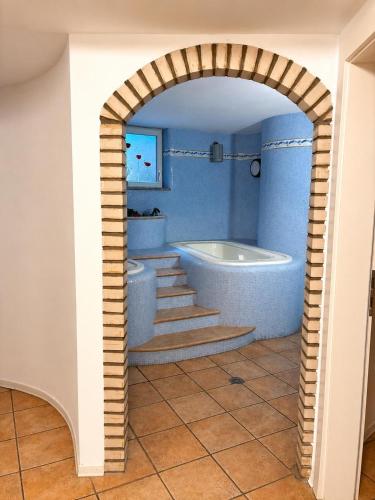 ein Torbogen in einem Badezimmer mit Badewanne und Treppe in der Unterkunft Hotel Ai Pini in Vigo di Fassa