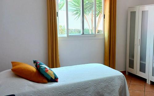 a bedroom with a bed and a window with a palm tree at Casa Yahshua in Villaverde