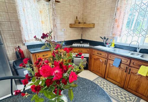 a kitchen with red flowers in a vase on a table at Haus Megan in Mahe