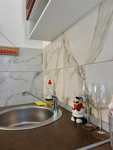 a kitchen counter with a sink and two wine glasses at APARTMAN BAMBUS in Lug
