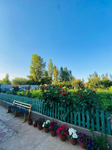 a bench in a garden with flowers and plants at Bloom Guest House in Tërt-Kul'