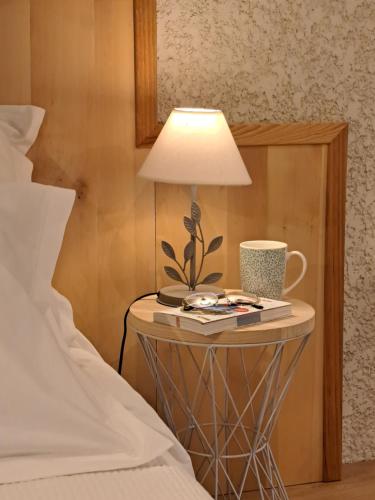 Ein Tisch mit einer Lampe darauf neben einem Bett in der Unterkunft Adorelys séjour bien être - spa et massage in Saint-Cassien