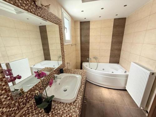 a bathroom with a tub and a large mirror at Olympus Views II in Leptokarya