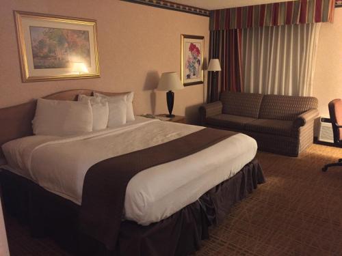Americas Best Value Inn & Suites-Boise في بويز: غرفة فندقية بسرير كبير واريكة