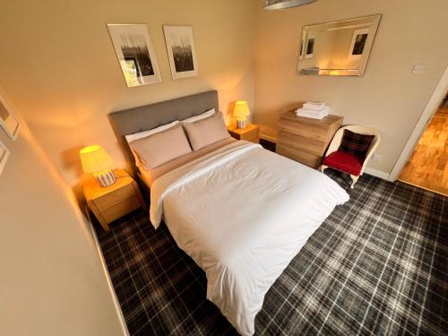 a bedroom with a white bed with two lamps and a chair at Taigh Tuaram in Carloway