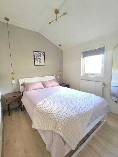 ein Schlafzimmer mit einem großen weißen Bett und rosa Kissen in der Unterkunft Chalet Descansar op de Veluwe in Beekbergen