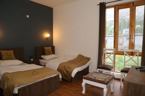 a hotel room with two beds and a window at Hunza Oriole Hotel in Alīābād