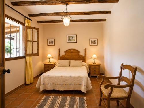a bedroom with a bed and a chair and a window at Villa La Clavelina Rocabella in El Chorro