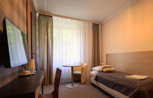 a bedroom with a bed and a table and a television at Pensjonat Irena in Muszyna
