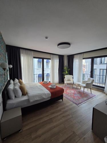 a bedroom with a large bed and chairs and windows at Zulu Suites in Istanbul