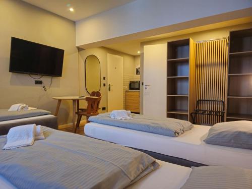 a bedroom with two beds and a flat screen tv at ARRIVEL Apartements Heimstetten in Kirchheim