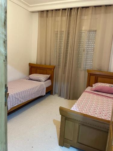 two twin beds in a room with curtains at Sweet Home in Tunis