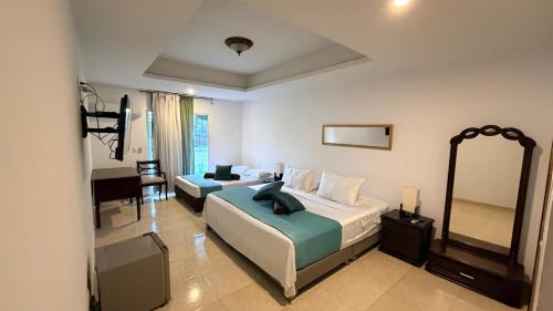 a bedroom with two beds and a desk and a mirror at hotel turqueza inn in Armenia