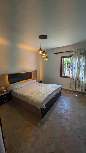 a bedroom with a bed and a window and a chandelier at Villa Saif in Marina Smir
