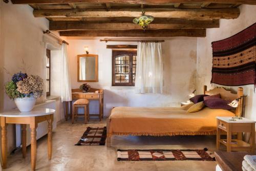 a bedroom with a bed and a table and a window at Kamares Private Pool stone Villa in Makhairoí
