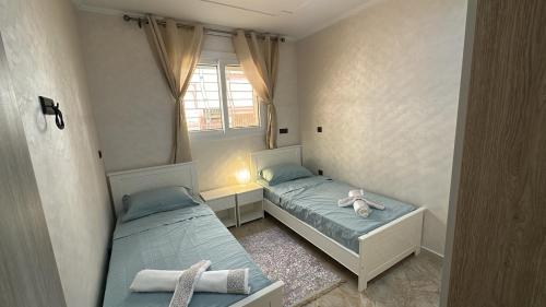 two beds in a small room with a window at Appartement Agadir T2 pour couples maries et familles in Agadir