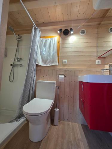 a bathroom with a toilet and a red cabinet at Ailéa Tiny House avec jacuzzi privatif in Beaumes-de-Venise