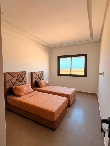 two beds in a room with a window at Magic House T5 -El Mansouria in Mansouria