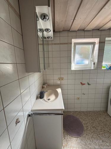 un piccolo bagno con lavandino e specchio di MaRe FeWo a Hettingen