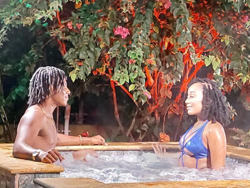 Ein Mann und eine Frau sitzen in einem Whirlpool in der Unterkunft Bamboo View in Loango
