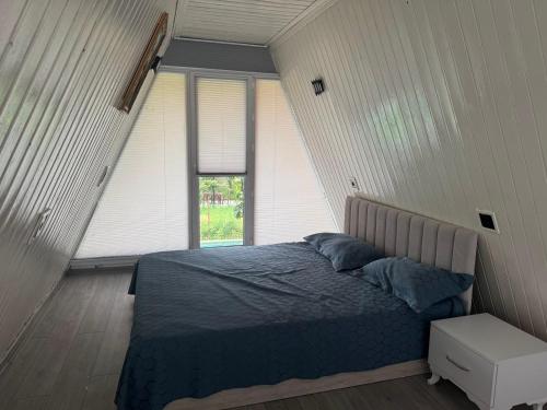 a bedroom with a bed with blue sheets and a window at xanagah aframe in Qala