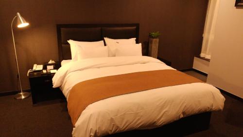 a bedroom with a large bed with white sheets at Gangneung Tourist Hotel in Gangneung