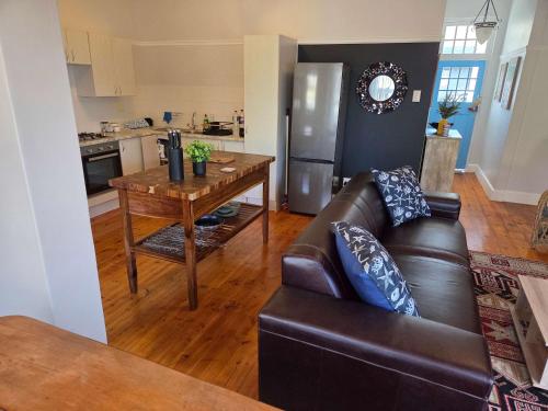 a living room with a leather couch and a table at Beach Street Self-Catering in Mossel Bay