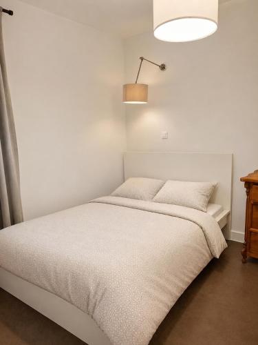 a white bedroom with a bed and a lamp at Apartament na Wzgórzu in Wieliczka