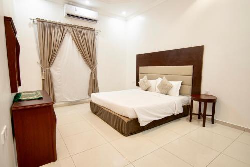 a bedroom with a bed and a table and a window at شقق راف التميز in Umm Salam