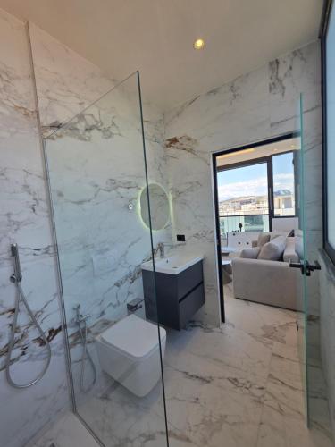 a bathroom with a shower and a toilet and a sink at Rooftop panoramic jacuzzi room in Ksamil