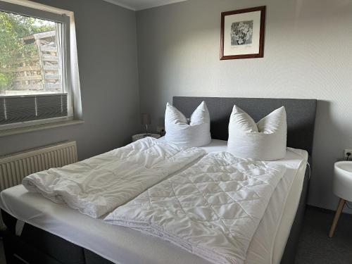 a bedroom with a bed with white sheets and pillows at Ferienhaus Katja in Göhren