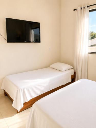 a bedroom with two beds and a flat screen tv at Ap7 - Studio Completo a Minutos das Compras no Paraguai in Guaíra