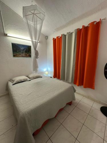 a bedroom with orange curtains and a bed in it at Appt Cosy Belcourt in Baie-Mahault