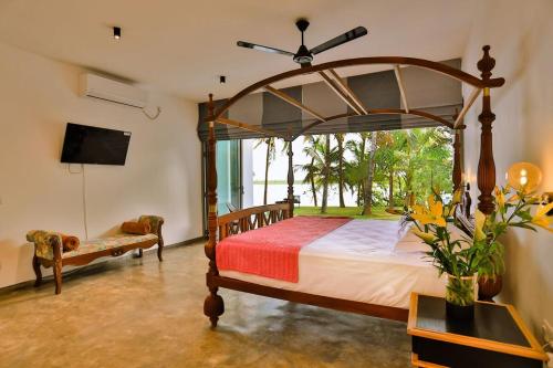 a bedroom with a canopy bed and a tv at Infinity Whisper in Kosgoda