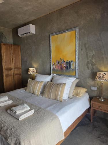 a bedroom with a large bed with a painting on the wall at Les Terrasses Suites in Calheta